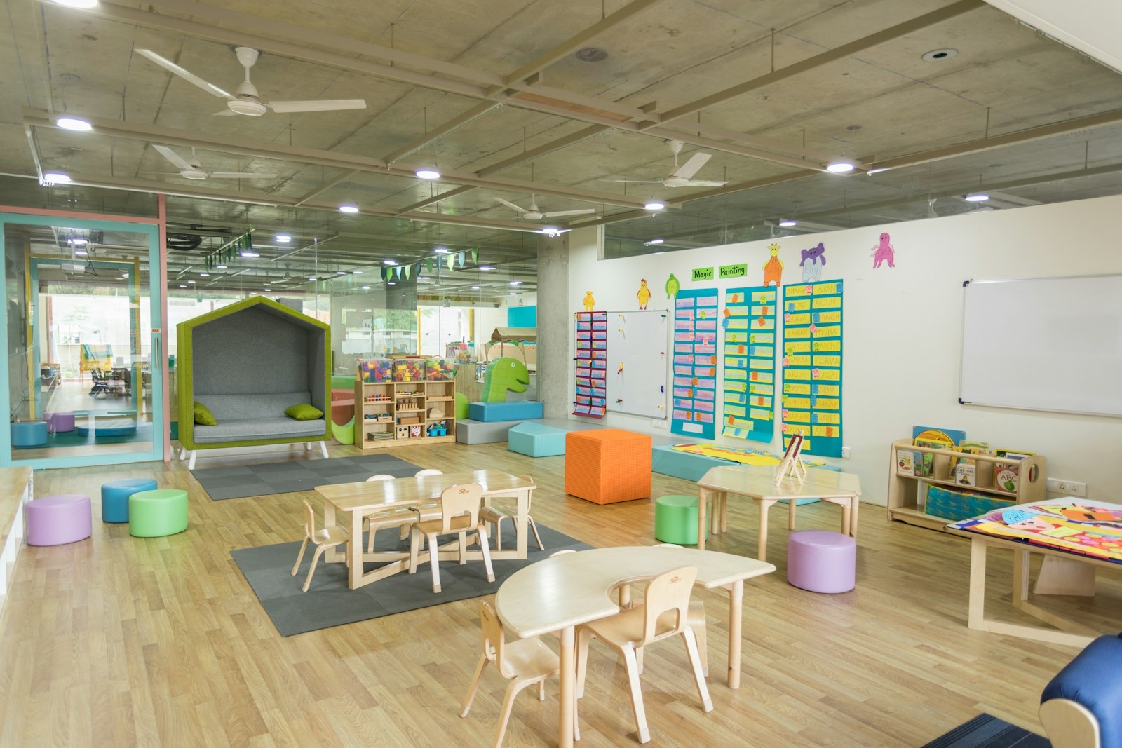 A bright classroom with low shelves of books and a reading nook
